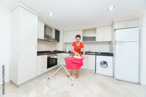 Photo: Housewife ironing laundry in middle of the kitchen Housewife ironing laundry in middle of the kitchen