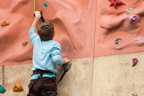 Photo: Young guy with climbed equipment rises to the climbing wall. Young guy with climbed equipment rises to the climbing wall.