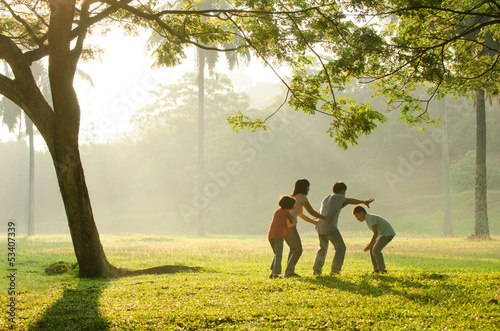 Photo: an asian family having fun playing in the park early morning an asian family having fun playing in the park early morning