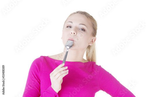 Photo: Portrait of young smiling woman with spoon in her mouth. Portrait of young smiling woman with spoon in her mouth.