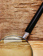 edge of the old newspaper and magnifying glass on a wooden backg