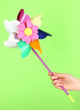 Photo: Colored pinwheel in hand on green background Colored pinwheel in hand on green background