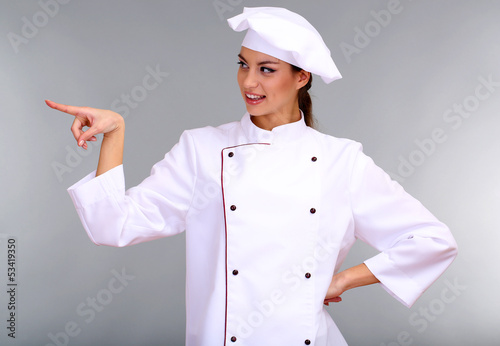 Photo: Portrait of young woman chef on grey background Portrait of young woman chef on grey background