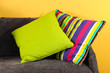 Colorful pillows on couch on yellow background
