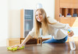 Happy  girl dusting table with detergent polish