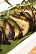 Grilled eggplant slices on a plate with fresh rosemary