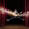 Artist jumping on stage playing guitar