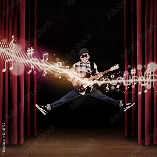 Photo: Artist jumping on stage playing guitar Artist jumping on stage playing guitar