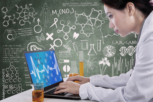 Photo: Beautiful scientist working with laptop at workplace Beautiful scientist working with laptop at workplace