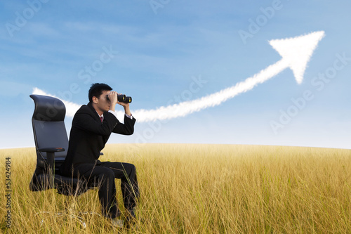Photo: Businessman using binoculars looking at growing chart cloud Businessman using binoculars looking at growing chart cloud