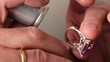 a goldsmith inspecting a golden ring with a diamond