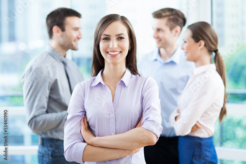 Photo: Businesswoman with coworkers in background Businesswoman with coworkers in background