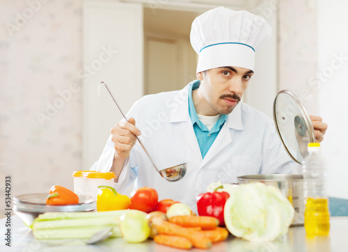 Photo: cook man works at kitchen cook man works at kitchen