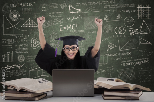Photo: Happy female graduate raise hands in class Happy female graduate raise hands in class