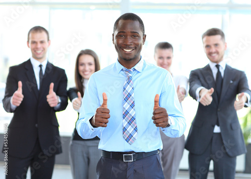 Photo: Successful young business people showing thumbs up sign Successful young business people showing thumbs up sign