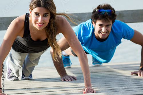 Photo: Couple doing push ups near the sea Couple doing push ups near the sea