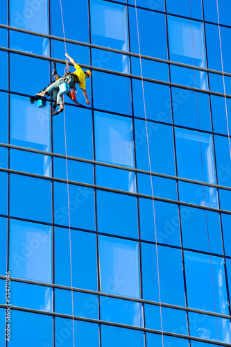 Photo: Washer wash the windows of modern skyscraper Washer wash the windows of modern skyscraper