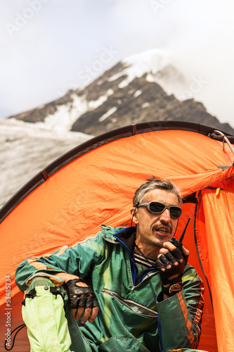 Photo: The rescuer in mountains talks on handheld transceiver The rescuer in mountains talks on handheld transceiver