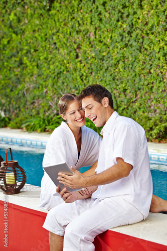 Photo: Couple at pool with tablet PC Couple at pool with tablet PC