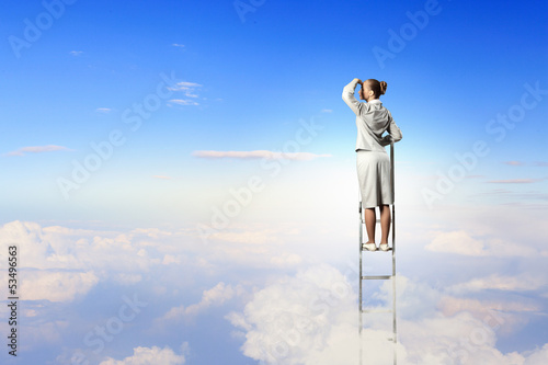 Photo: Businesswoman standing on ladder Businesswoman standing on ladder