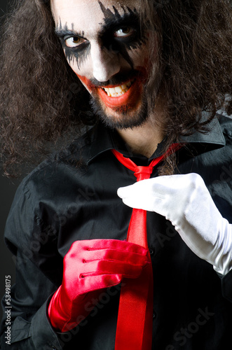 Photo: Joker personification with man in dark room Joker personification with man in dark room