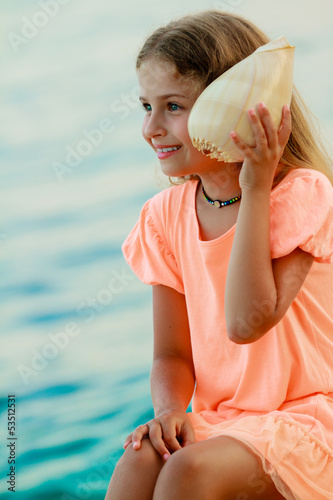 Photo: Summer relax - lovely girl with shell on the beach Summer relax - lovely girl with shell on the beach