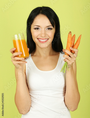 Photo: Girl with fresh carrot and juice on green background Girl with fresh carrot and juice on green background