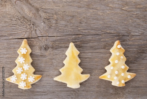 Photo: three christmas tree cookies on wood brackground three christmas tree cookies on wood brackground