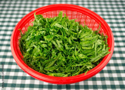 Photo: Chopped mustard greens in a red strainer bowl Chopped mustard greens in a red strainer bowl