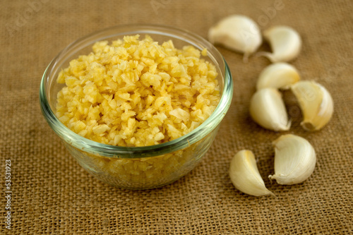 Photo: Finely chopped garlic with cloves in the background Finely chopped garlic with cloves in the background