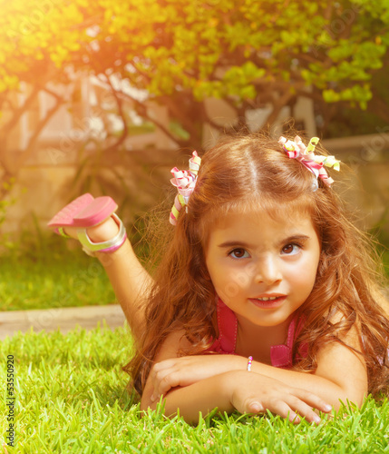 Photo: Little girl lying down on green grass Little girl lying down on green grass