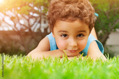 Photo: Baby boy lying down on green field Baby boy lying down on green field