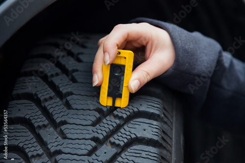 Photo: Frau misst Reifenprofil eines Autoreifen Frau misst Reifenprofil eines Autoreifen