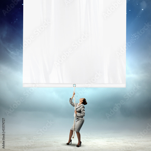 Photo: Businesswoman pulling blank banner Businesswoman pulling blank banner