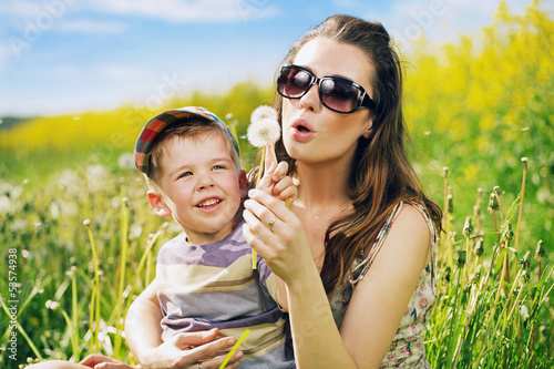 Photo: Pretty young mother playing dandelions with son Pretty young mother playing dandelions with son
