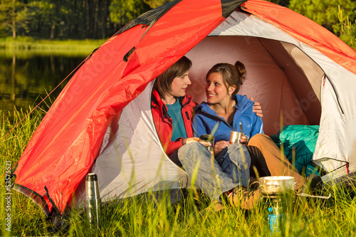 Photo: Camping teenagers sitting and embracing in tent Camping teenagers sitting and embracing in tent
