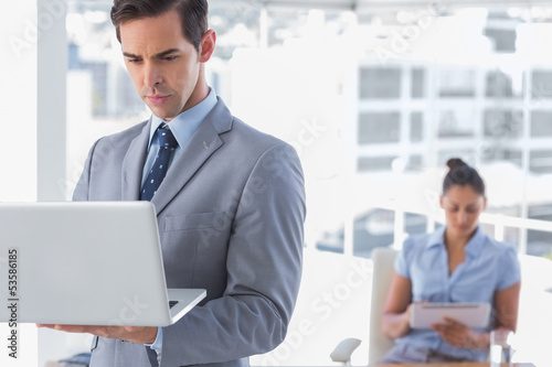 Photo: Businessman standing with laptop Businessman standing with laptop