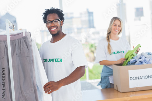 Photo: Pretty volunteers taking clothes out of a donation box Pretty volunteers taking clothes out of a donation box