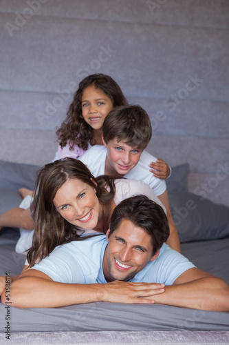 Photo: Happy family playing together on the bed Happy family playing together on the bed