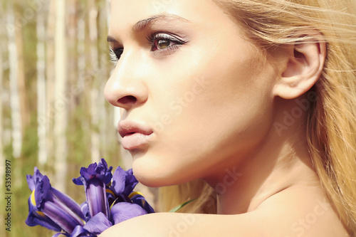 Photo: Beautiful blond woman with blue flowers in forest Beautiful blond woman with blue flowers in forest