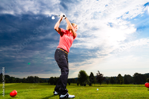 Photo: Young golf player on course doing golf swing Young golf player on course doing golf swing