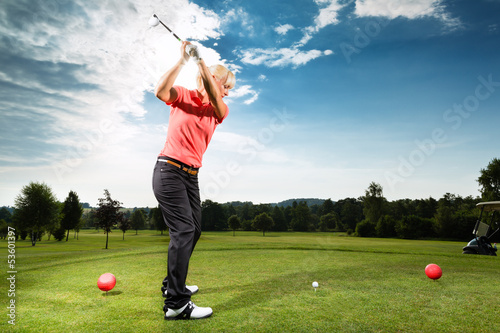 Photo: Young golf player on course doing golf swing Young golf player on course doing golf swing