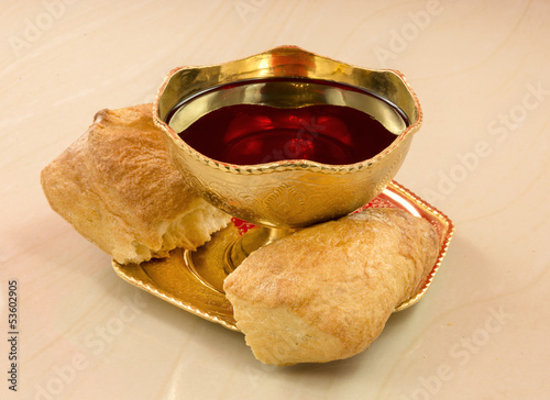 Photo: golden chalice with red wine and bread broken into on a marble t golden chalice with red wine and bread broken into on a marble t
