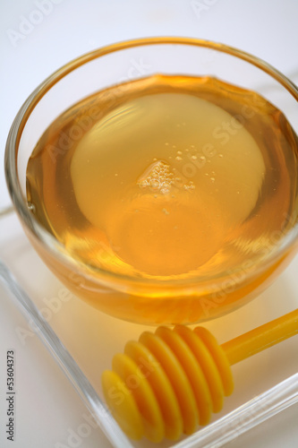 Photo: Honey jar and a honey dipper on white background Honey jar and a honey dipper on white background