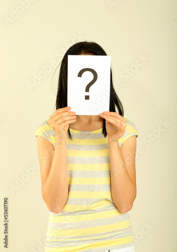 Photo: Woman with question marks on grey background Woman with question marks on grey background