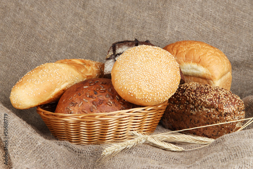 Photo: Baked bread in wicker basket on burlap background Baked bread in wicker basket on burlap background