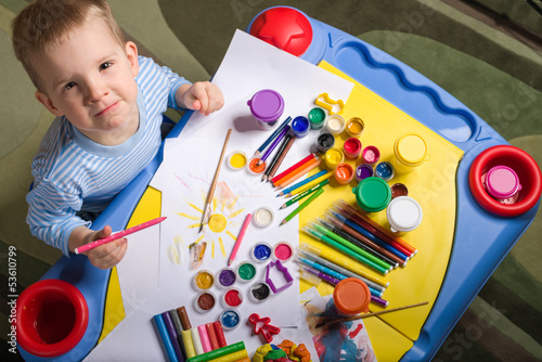 Photo: little boy painting at the table, top view little boy painting at the table, top view
