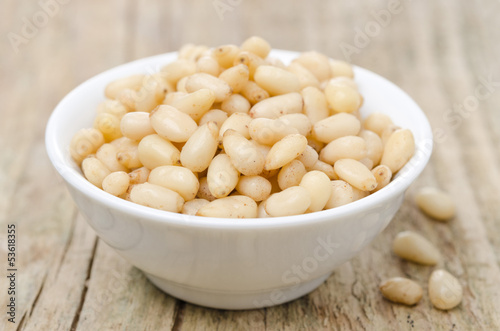 Photo: pine nuts in a bowl on wooden background close-up pine nuts in a bowl on wooden background close-up