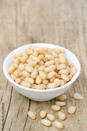 Photo: pine nuts in a bowl on wooden background pine nuts in a bowl on wooden background