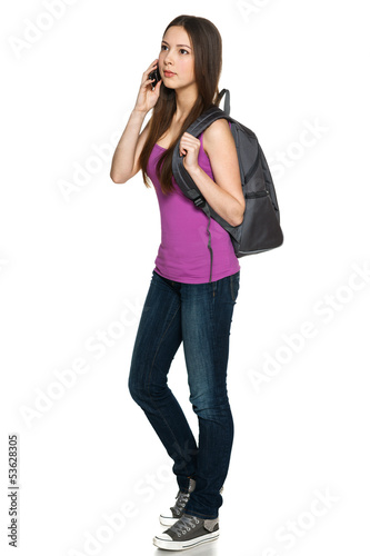 Photo: Full legnth of young female with backpack talking on cellphone Full legnth of young female with backpack talking on cellphone